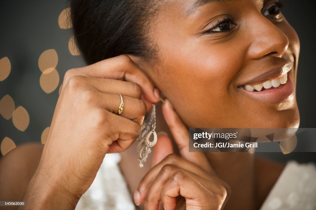 Black woman putting on earring