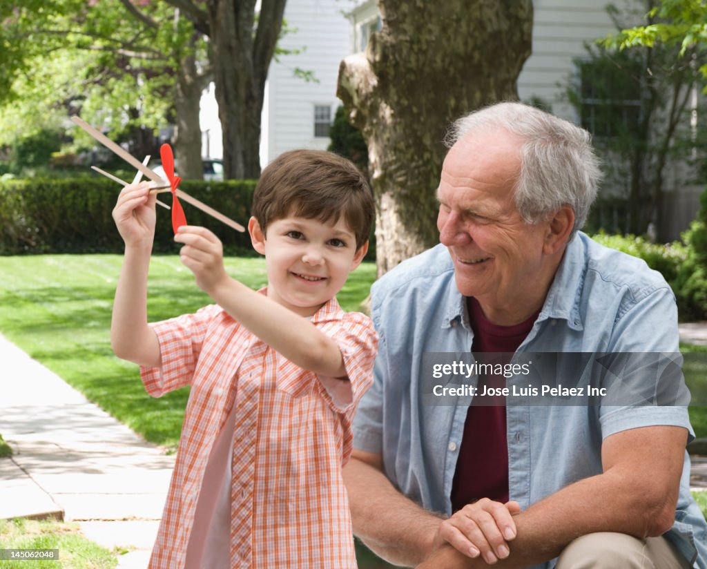 Caucasian boy and grandfather playing with toy airplane