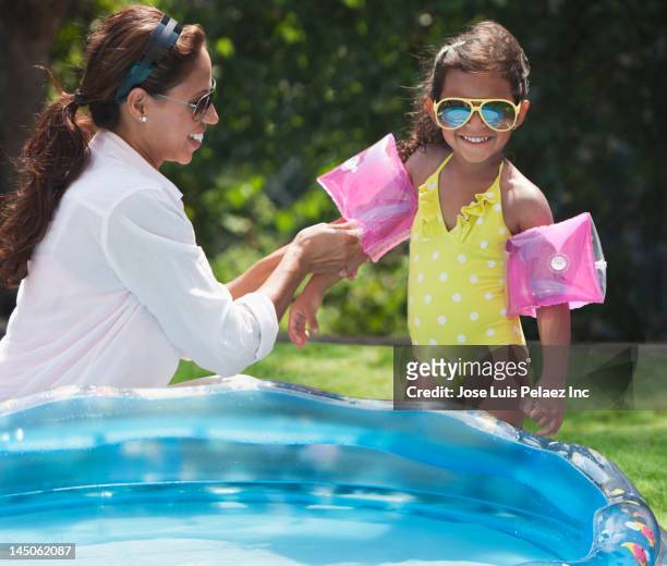 hispanic mother putting floaties on daughter - family no faces stockfoto's en -beelden