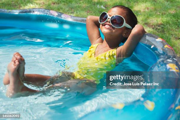 hispanic girl relaxing in kiddie pool - actividad de fin de semana fotografías e imágenes de stock