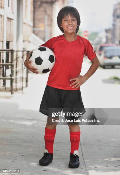 hispanic boy holding soccer ball on city sidewalk - boy brown hair stock pictures, royalty-free photos & images