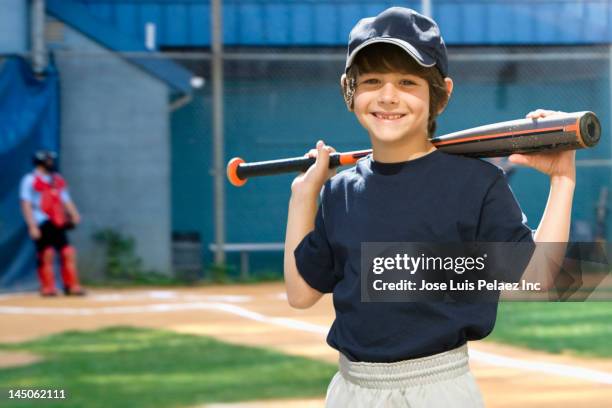 caucasian boy holding baseball bat on field - baseball uniform stock pictures, royalty-free photos & images