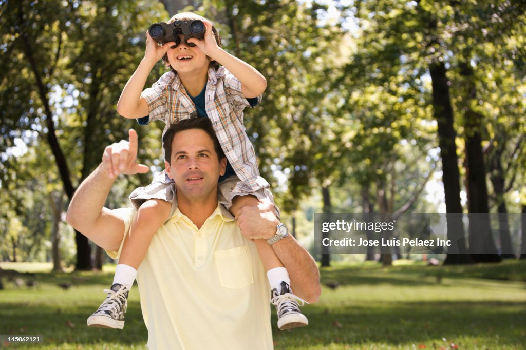 Caucasian man carrying son on shoulders in park