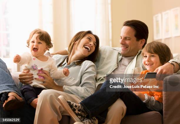 caucasian family watching television together - family tv stock-fotos und bilder