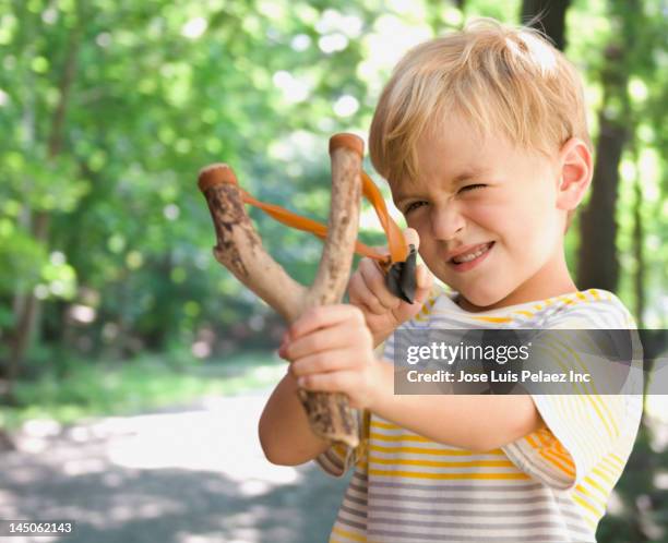 caucasian boy shooting slingshot - zwiesel stock-fotos und bilder