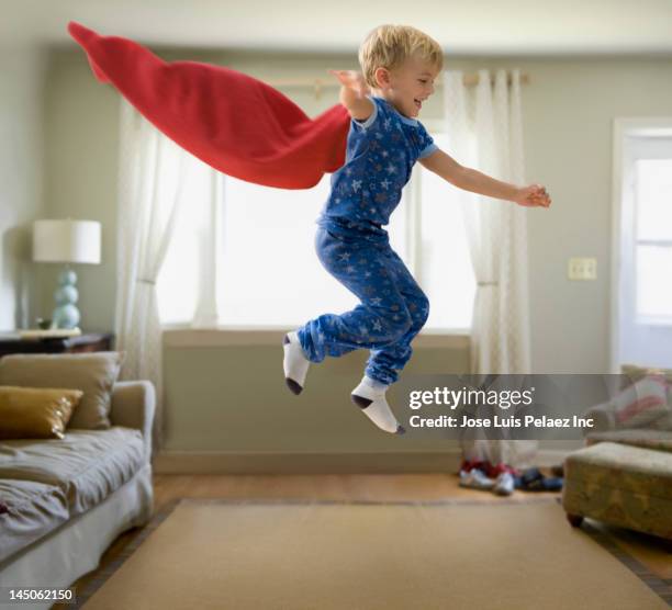 caucasian boy in superhero costume jumping through the air - superhero flying stock pictures, royalty-free photos & images