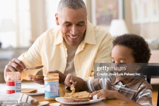 grandfather and grandson making peanut butter and jelly sandwiches - mantequilla de cacahuete fotografías e imágenes de stock