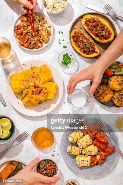 table filled with various dishes including chop suey, stuffed potatoes, fajitas, rice muffins, ricotta rolls and various salads - aperitivo plato de comida fotografías e imágenes de stock