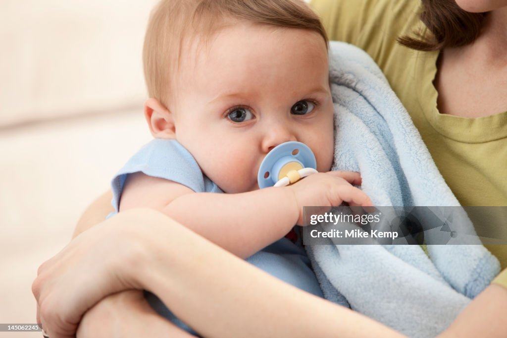 Caucasian baby boy with pacifier in mother's arms