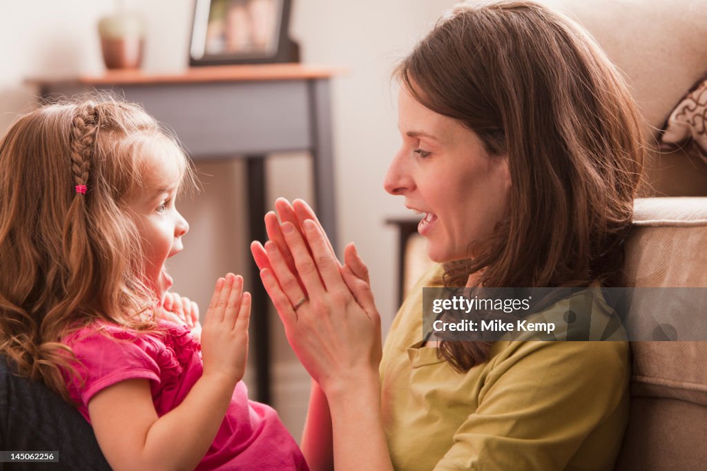 Caucasian mother and daughter playing clapping game