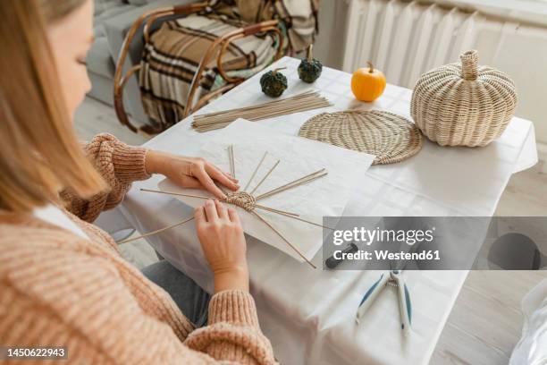 over shoulder view of woman weaving basket - basket weaving stock pictures, royalty-free photos & images