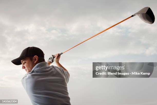 caucasian golfer swinging golf club - golf swing from behind stock pictures, royalty-free photos & images