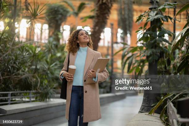 smiling businesswoman holding laptop and disposable cup - business woman brown hair stock pictures, royalty-free photos & images