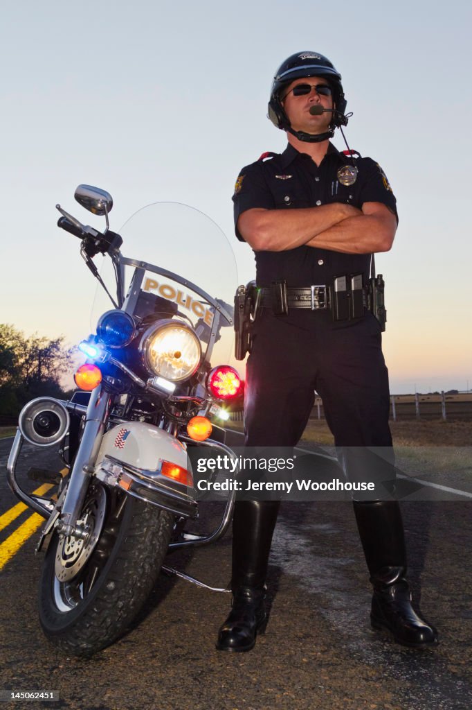 Caucasian policeman standing near motorcycle