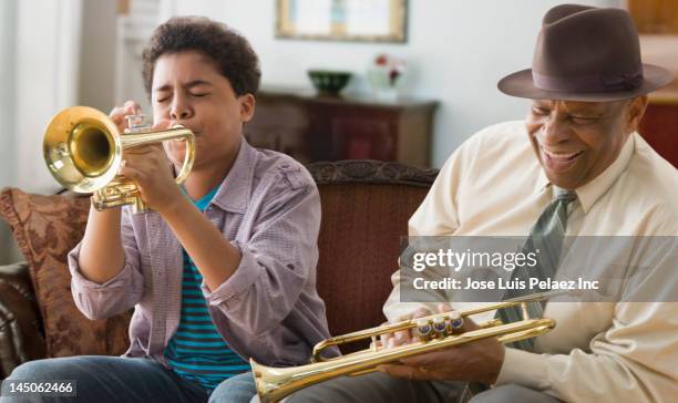 black grandson and grandfather playing trumpet together - トランペット ストックフォトと画像