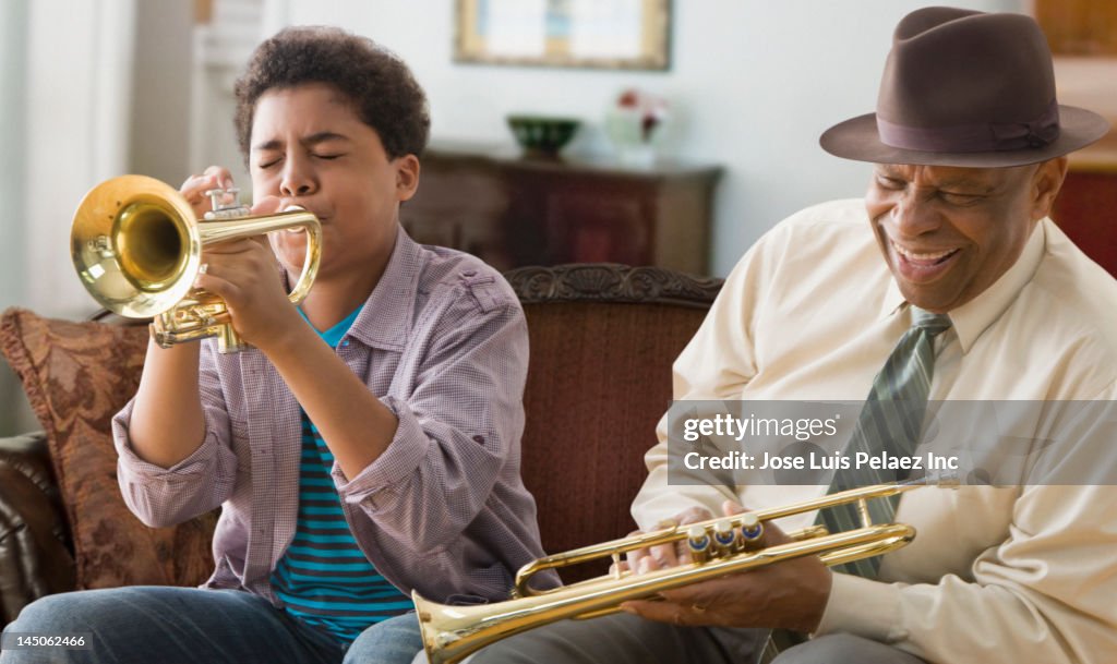 Black grandson and grandfather playing trumpet together