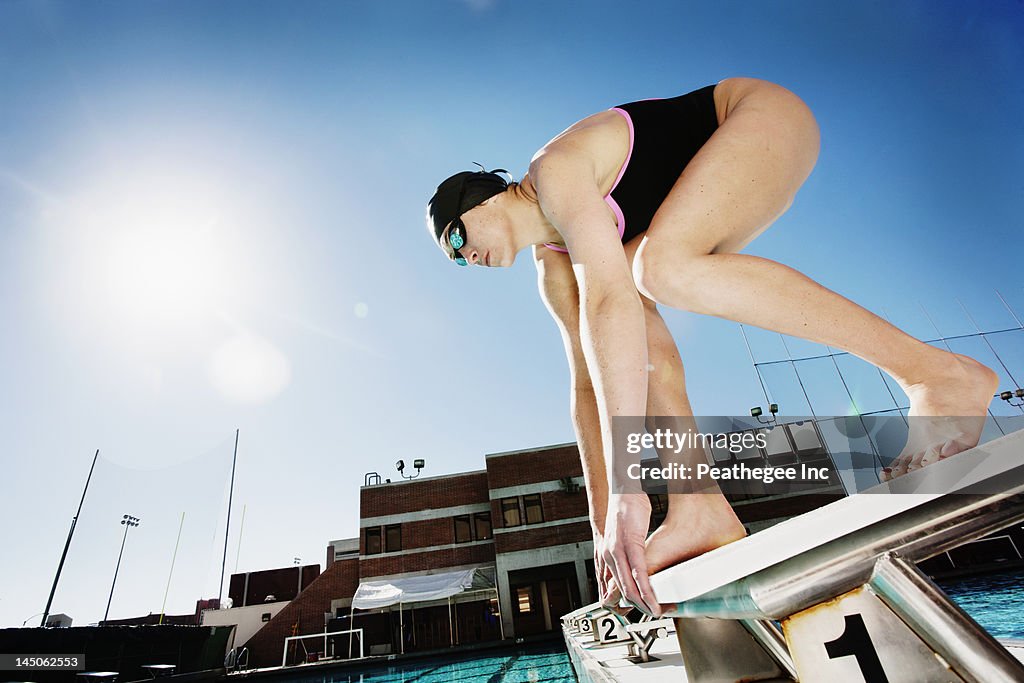 Competitive swimmer crouching on starting block