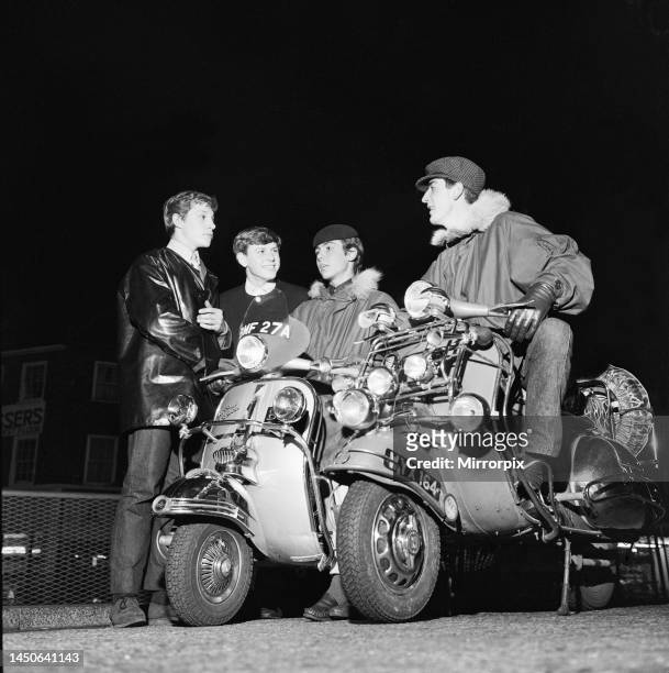 Two Mods sit on their scooters wearing fur collared Parka coats. The bikes are covered with spot lights, a mod fashion statement. 24th October 1963.
