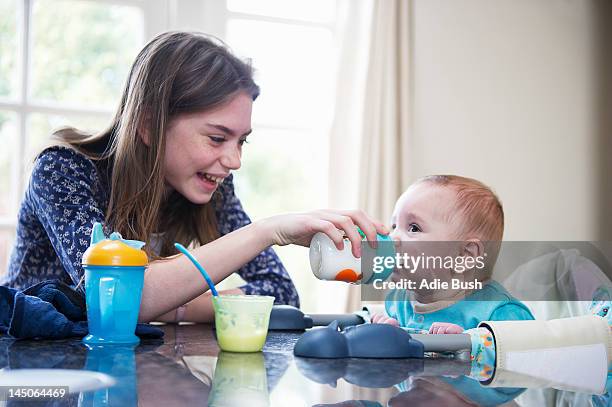 fille de nourrir bébé frère à table - nurse photos et images de collection