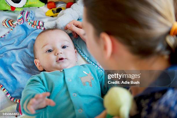 girl playing with baby brother on bed - bush baby stockfoto's en -beelden