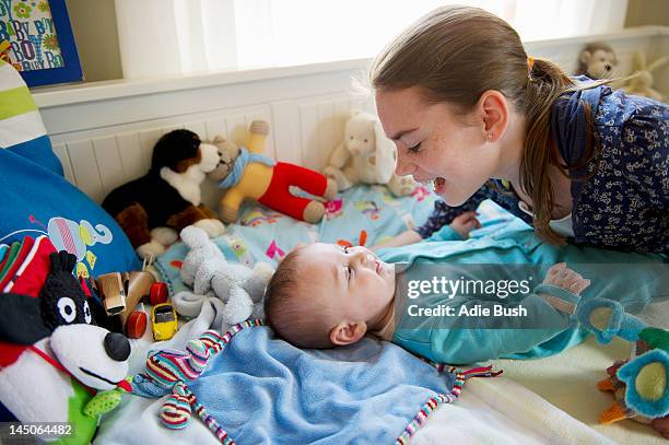 girl playing with baby brother on bed - bush baby stockfoto's en -beelden