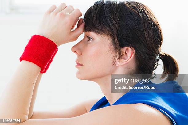 woman resting forehead in hands - wristband stock pictures, royalty-free photos & images