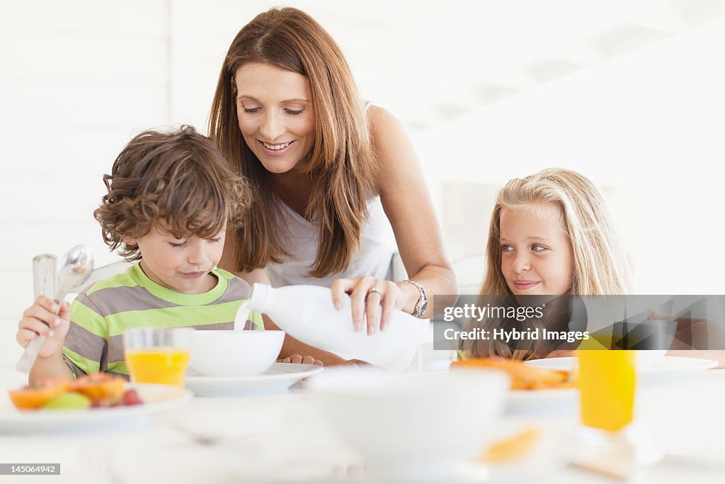 Mother pouring milk for son