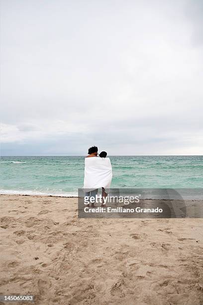 a young couple wrapped in a beach towel standing on the beach - hot puerto rican women stock-fotos und bilder