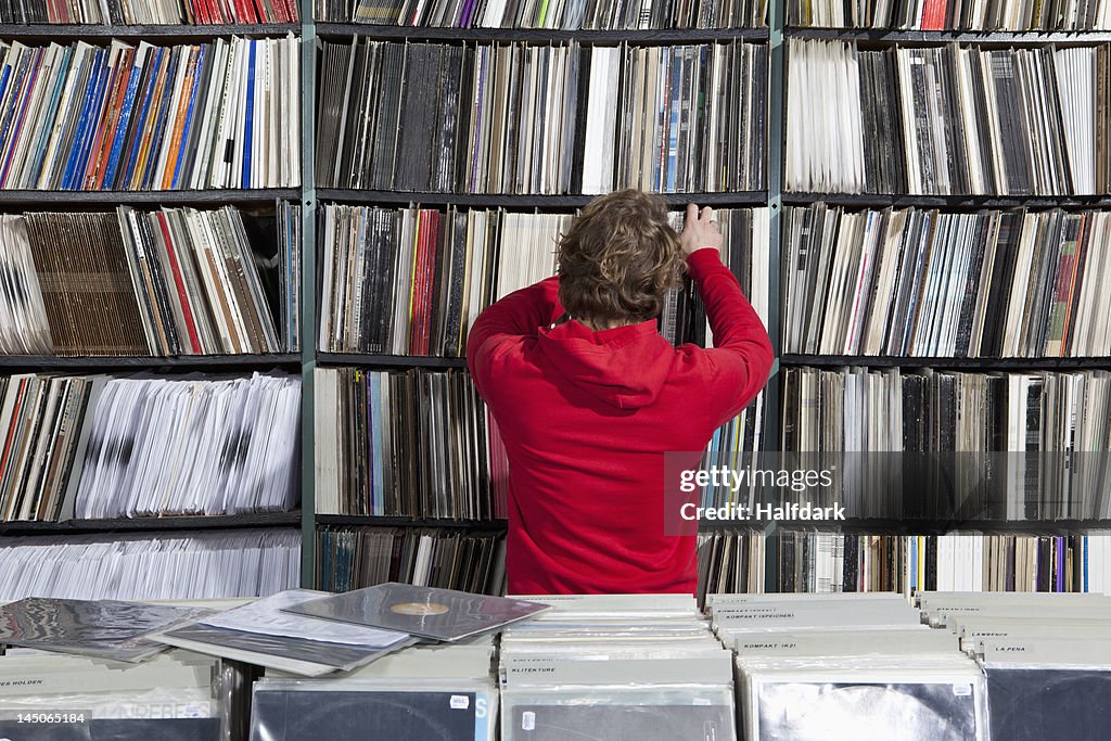 A young man selecting a record from a shelf in a record store