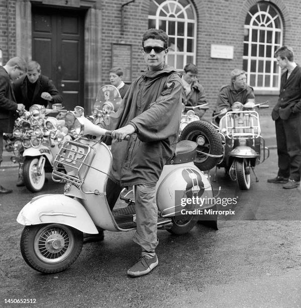 Mods wearing suits and parka's, on scooters covered with extra lights and wing mirrors. May 1964.