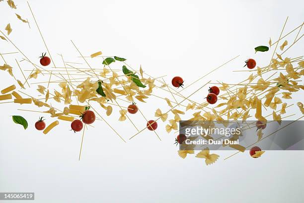 raw pasta, tomatoes, and basil against a white background - throwing tomatoes stock pictures, royalty-free photos & images