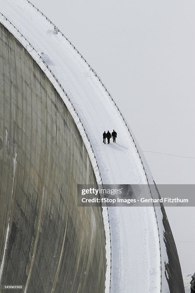 Three people walking above the Zervreila Dam, Switzerland