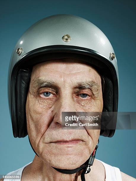 a headshot of a frowning senior man wearing a crash helmet - crash helmet fotografías e imágenes de stock