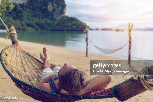 man relaxing on hammock by the beach at sunrise - homens de idade mediana imagens e fotografias de stock