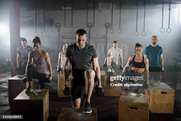 athletic people having cross training with dumbbells in a gym. - cross training stock pictures, royalty-free photos & images