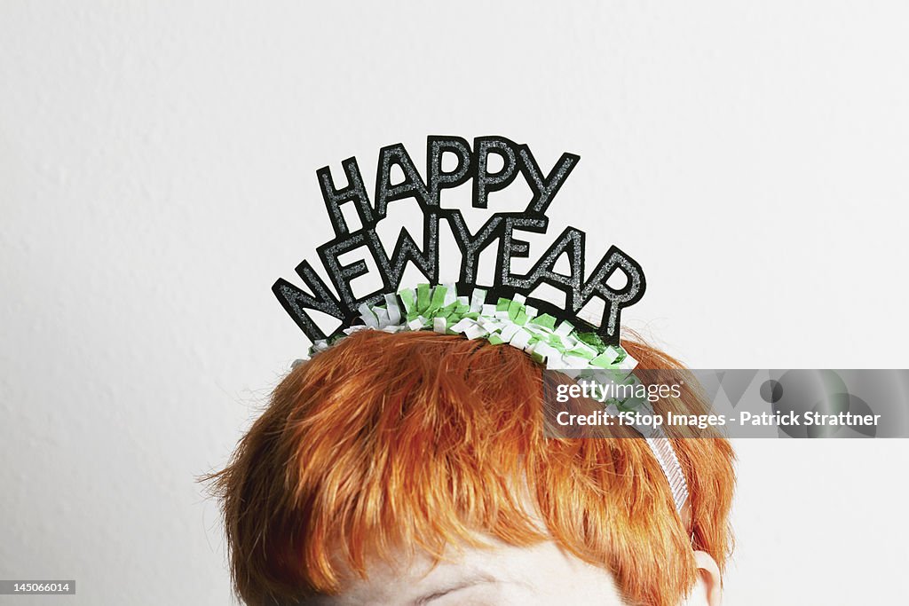 A woman wearing a party tiara with Happy New Year on it, top of head