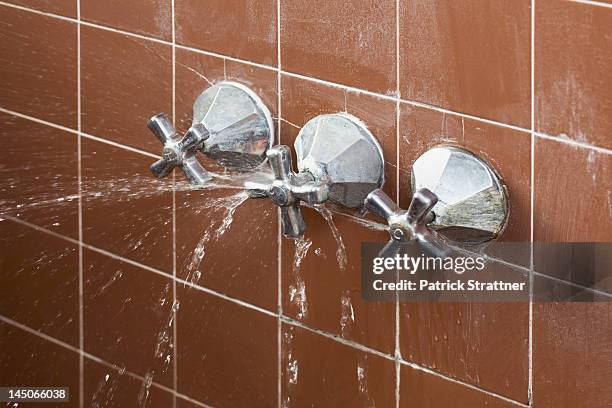 a shower faucet handle spraying leaking water - bathroom closeup stock pictures, royalty-free photos & images