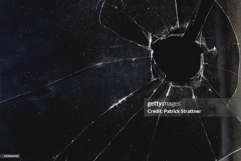 A window with a hole broken through the glass, night