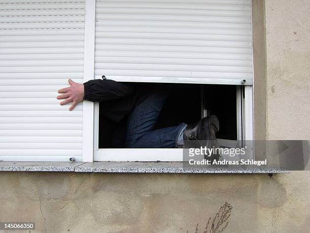 a man climbing through a window - cambrioleur photos et images de collection