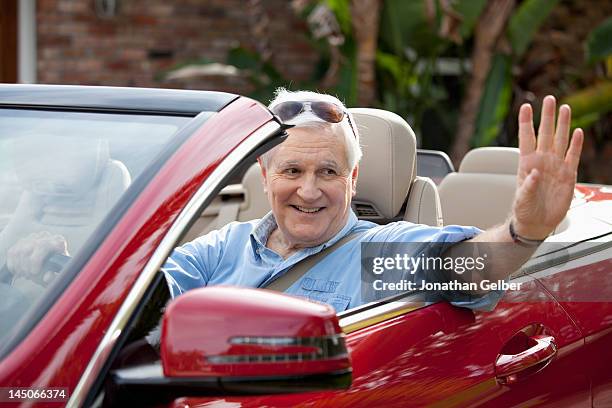 a senior man waving from driver's seat of convertible - waving hands goodbye photos et images de collection