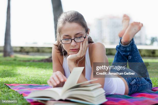 girl lying down reading in park - barefoot feet up lying down girl stock-fotos und bilder