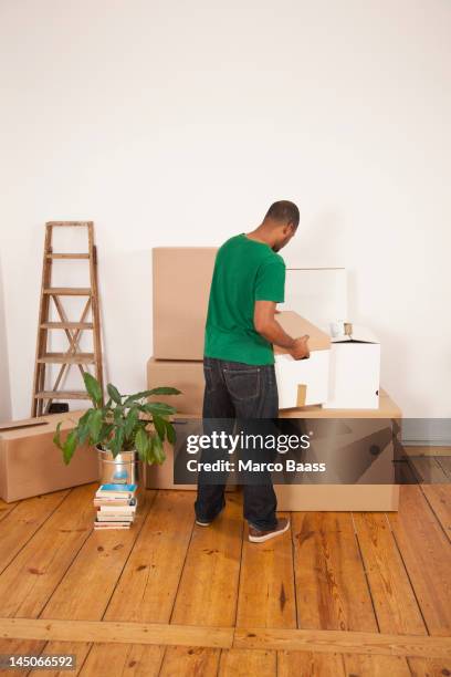 a man lifting a moving box to put it on top of other boxes - box lifting technique stock-fotos und bilder