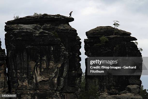 a person preparing to rappel down a rock formation, saxon switzerland, saxony, germany - saxony stock pictures, royalty-free photos & images