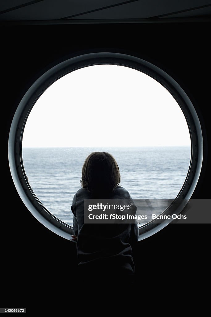 Rear view of a boy looking through a porthole
