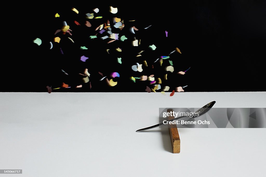 Confetti floating above a spoon leaning on a wooden block