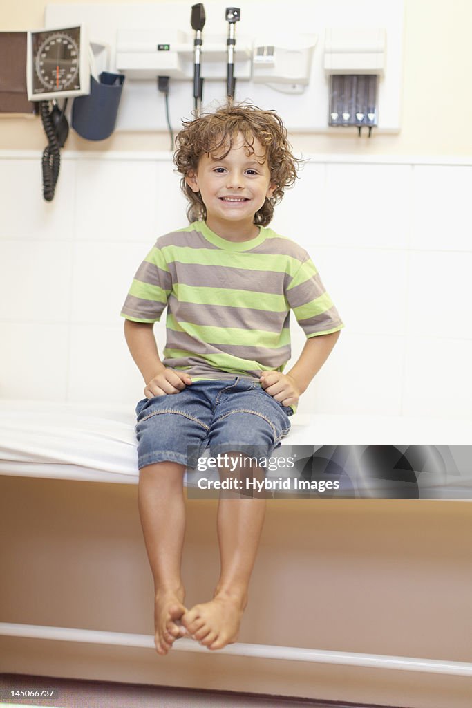 Boy sitting on table in doctors office