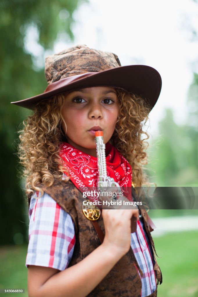Girl in cowboy hat with toy pistol