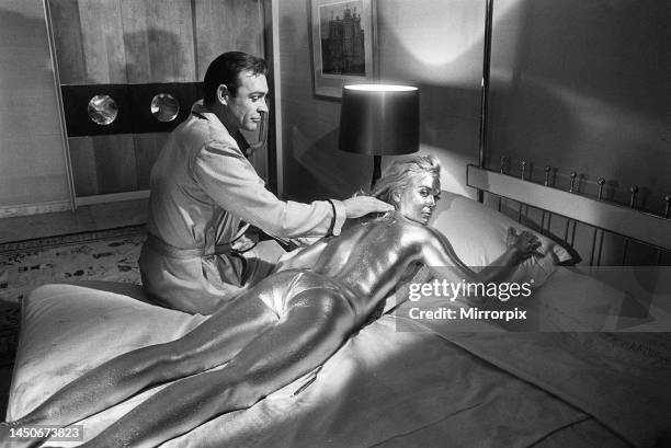 Shirley Eaton lies covered in gold paint on set during the filming of Goldfinger. Sean Connery plays James Bond. 20th April 1964.