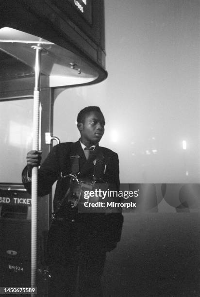 London Transport bus conductor looks out from the platform of his Routemaster bus during the London smog of December 1962. 6th December 1962.