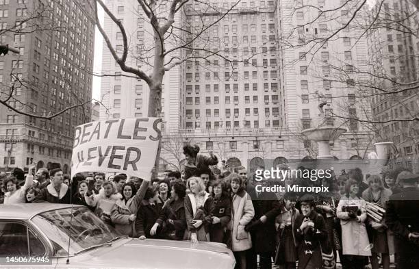 The Beatles in New York City. Excited fans cheer and wave banners on the street as the Beatles car passes. 9th February 1964.